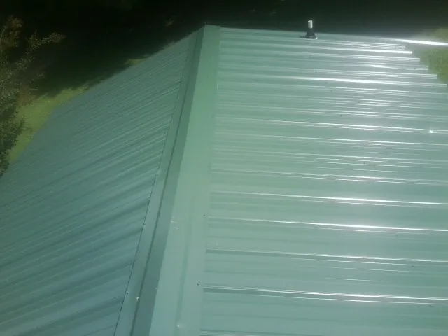 New green metal panels meeting at the ridge of a roof — Flat Roof Repair work by our crew in Ross