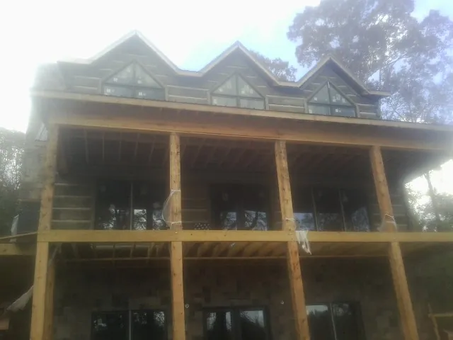 Dormers and porch framing on a large log home under construction — Roof Coating work by our crew in Ross