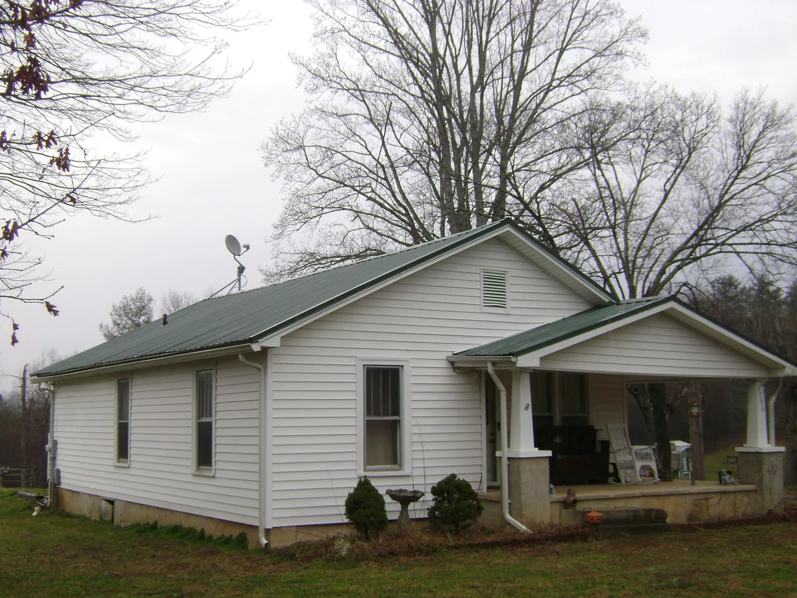 Green metal roof on a white bungalow with a side porch in Ross