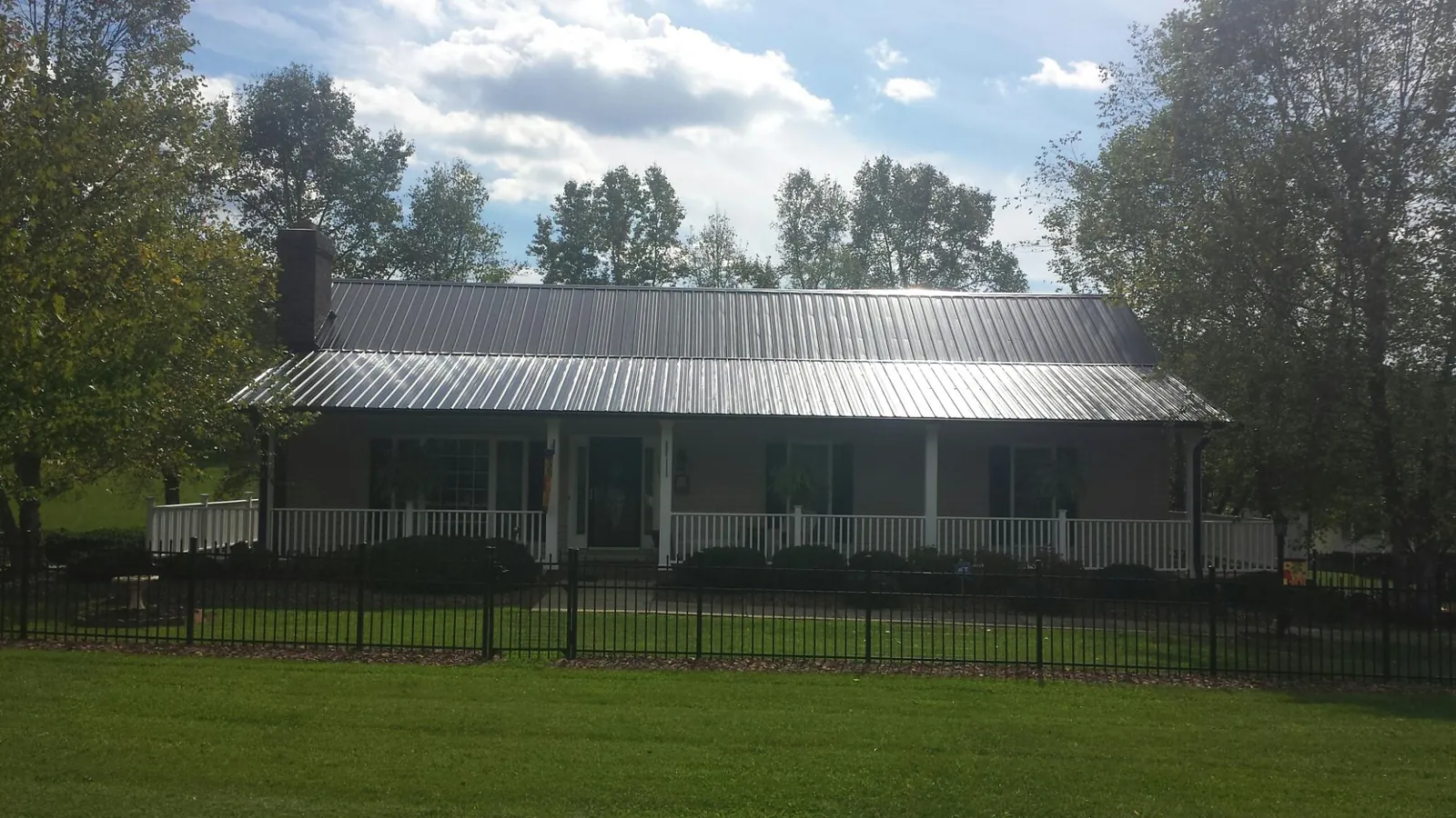 Gray metal roof on a brick ranch with a full width front porch — Gutter Guard Installation work by our crew in Ross