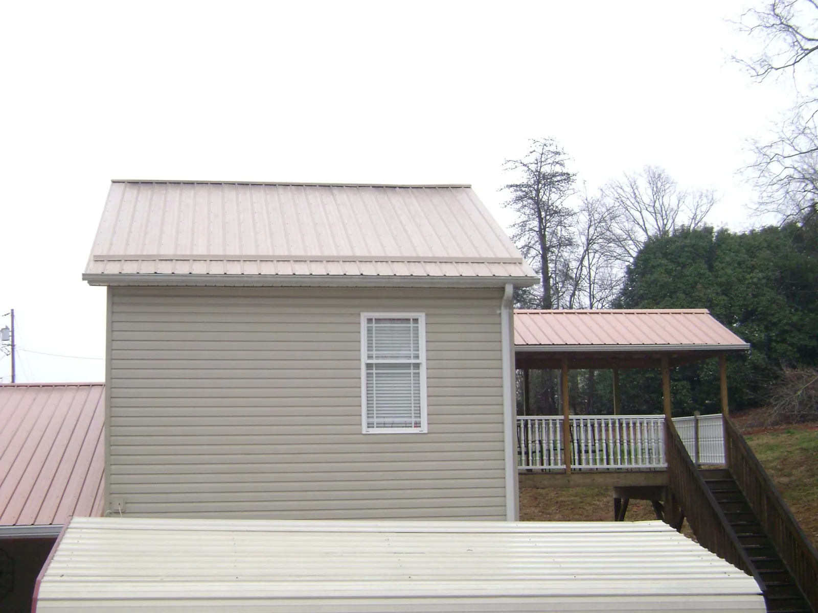 Tan metal roofs on a two story addition and attached porch, from a Roof Replacement job in Ross